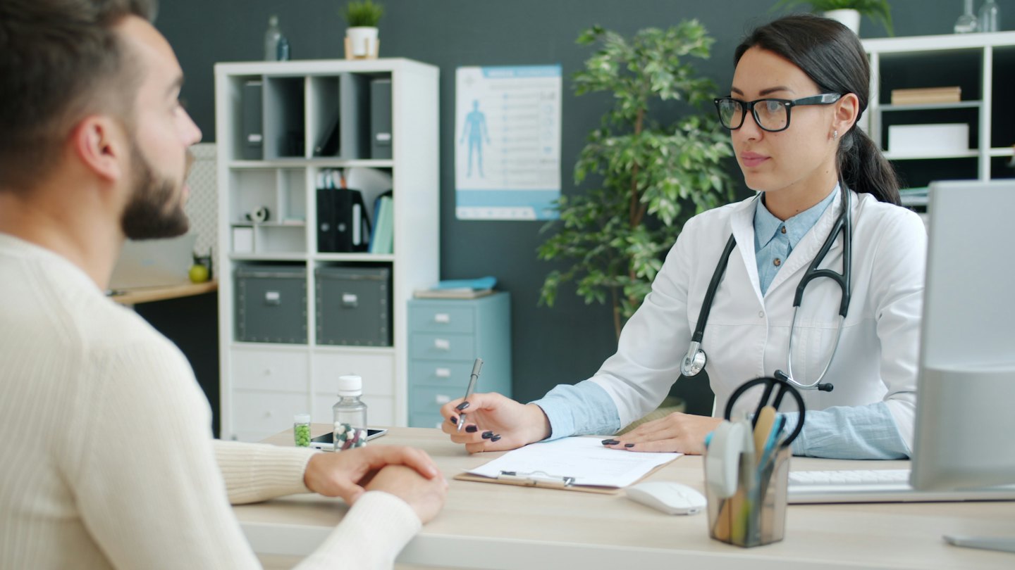 Medico con penna che consulta un paziente in ufficio.